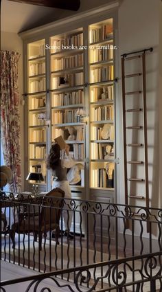 a woman sitting at a desk in front of a book case filled with books and papers