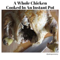 a whole chicken cooked in an instant pot on a cutting board next to a knife