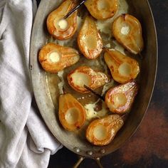 a pan filled with potatoes covered in sauce and butter on top of a wooden table