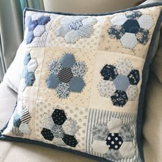 a blue and white patchwork pillow sitting on top of a couch