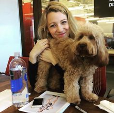 a woman sitting at a table holding a dog