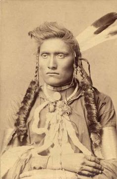 an old black and white photo of a native american man with feathers on his head