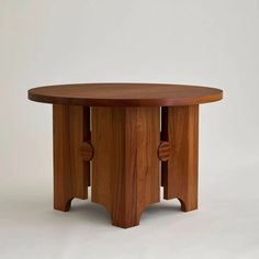 a round wooden table with three legs and two circles on the top, against a white background