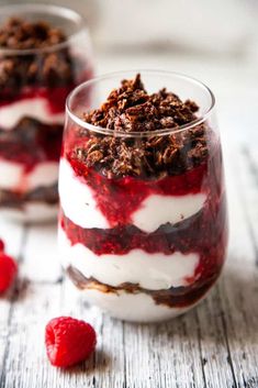 two desserts in small glasses with raspberries on the side