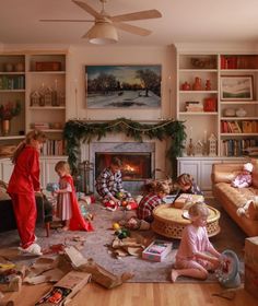 children are playing in the living room with their christmas presents on the floor and around the fire place