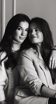 two women sitting next to each other posing for a black and white photo with their arms around one another