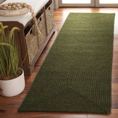 a green rug is on the floor next to a plant