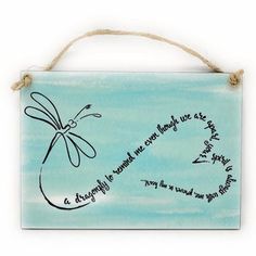 a wooden sign with writing on it and a dragonfly hanging from the front side