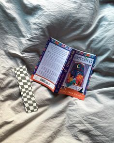 an open book with a tie laying on top of it next to a bed sheet