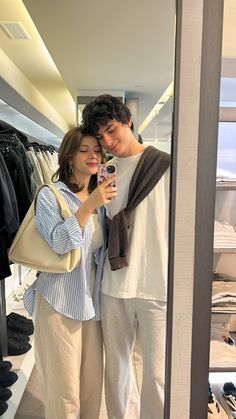 a man and woman taking a selfie in a clothing store