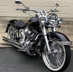 a black and chrome motorcycle parked in front of a garage door with its lights on