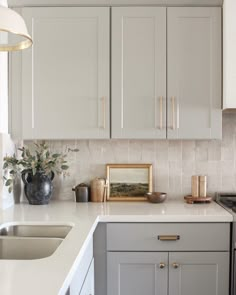 a kitchen with gray cabinets and white counter tops, gold trim on the cabinet doors