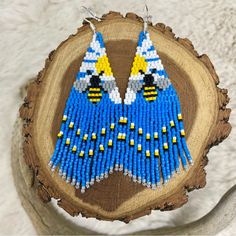 a pair of blue and yellow beaded earrings sitting on top of a piece of wood