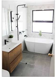 a white bath tub sitting under a bathroom window