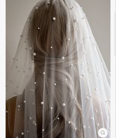 a woman wearing a veil with pearls on it's head and her hair in the back