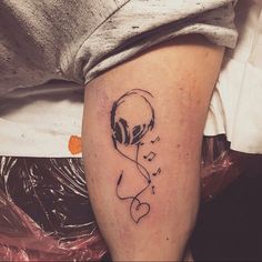 a person with headphones on their ears is sitting down and has a tattoo on his leg