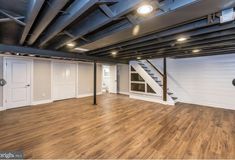 an empty room with hard wood flooring and exposed beams on the ceiling is lit by recessed lights