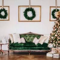 a living room decorated for christmas with green velvet couches and wreaths on the wall