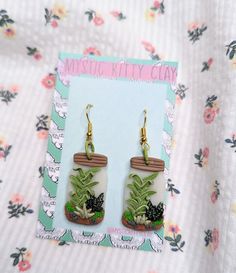 the earrings are decorated with plants and flowers