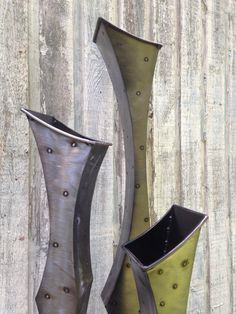 two tall metal vases sitting next to each other on a wooden surface with holes in them