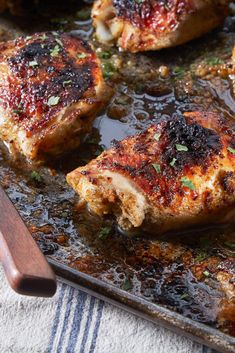 some meat is cooking on a pan with a spatula next to it and a wooden spoon