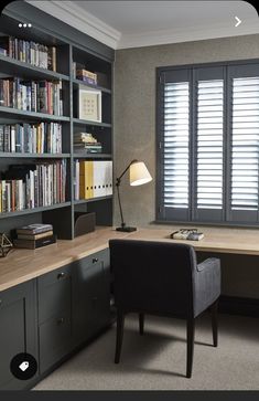 a home office with bookcases, desk and chair in front of the window