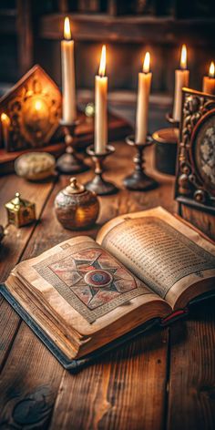 an open book sitting on top of a wooden table next to candles and other items