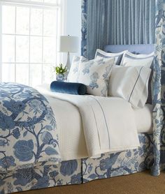 a bed with blue and white comforters in a bedroom next to a window,