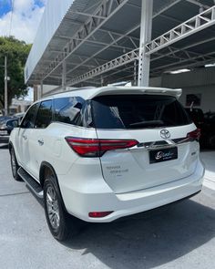 the rear end of a white toyota highland parked in front of a building with an awning