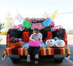 a young boy sitting in the back of a truck with decorations on it's bed