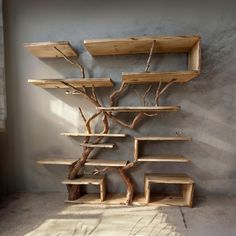 a wooden shelf with several shelves and a tree branch on it's side, in front of a concrete wall