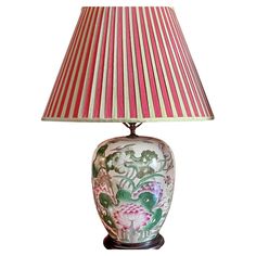 a lamp with a red and white striped shade on top of it, sitting on a table