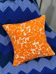 an orange and white pillow sitting on top of a blue blanket