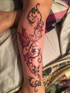 a woman laying in bed with a tattoo on her leg and butterfly on the side