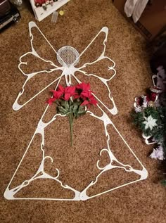 a metal angel decoration with red flowers on the floor