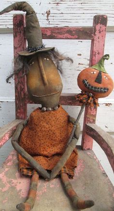 an old doll sitting on top of a wooden chair next to a small scarecrow