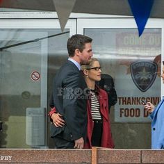 two women and a man are standing in front of a police station window talking to each other