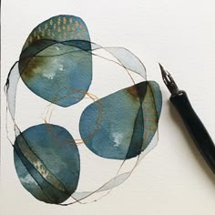 a pen is resting on a piece of paper that has been drawn with watercolors