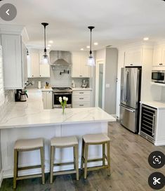 a large kitchen with white cabinets and marble counter tops, an island in the middle