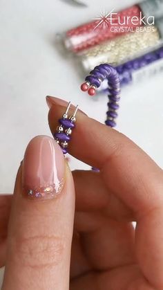 a woman's hand holding a purple beaded ring