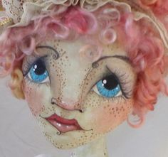 a close up of a doll with pink hair and blue eyes wearing a tiara