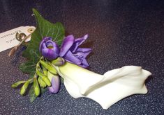 purple flowers and green leaves on a counter top with a name tag attached to it