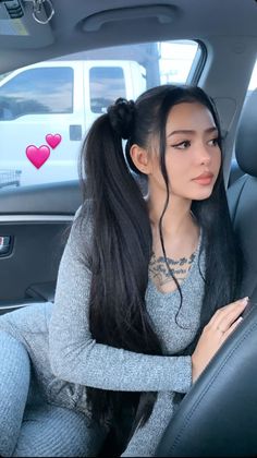 a woman sitting in the back seat of a car with long black hair and piercings