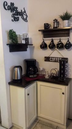 there is a coffee maker and some cups on the counter in this small kitchen area