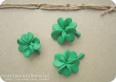 three green plastic flowers sitting on top of a piece of paper next to a string