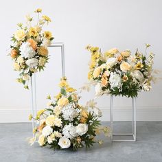 two vases filled with flowers sitting next to each other on top of a floor