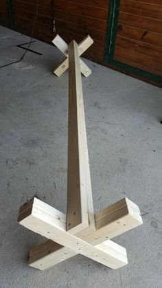 a wooden cross sitting on top of a cement floor next to a garage door and another object in the background