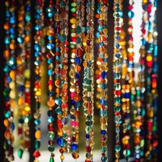 colorful beads hanging from the ceiling in front of a window