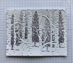 a piece of paper that has some trees on it and snow in the woods behind it