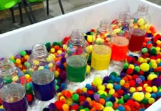 there are many different colored liquids in the tub with plastic balls around it and on the floor